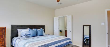 A bedroom with a bed, a bench, a ceiling fan, and a door.