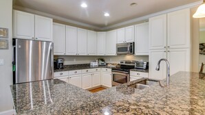 A modern kitchen with white cabinets, stainless steel appliances, granite countertops, and a built-in oven. - 4 Mi to Fenwick Island: Home w/ Pool Access & Deck (Selbyville)