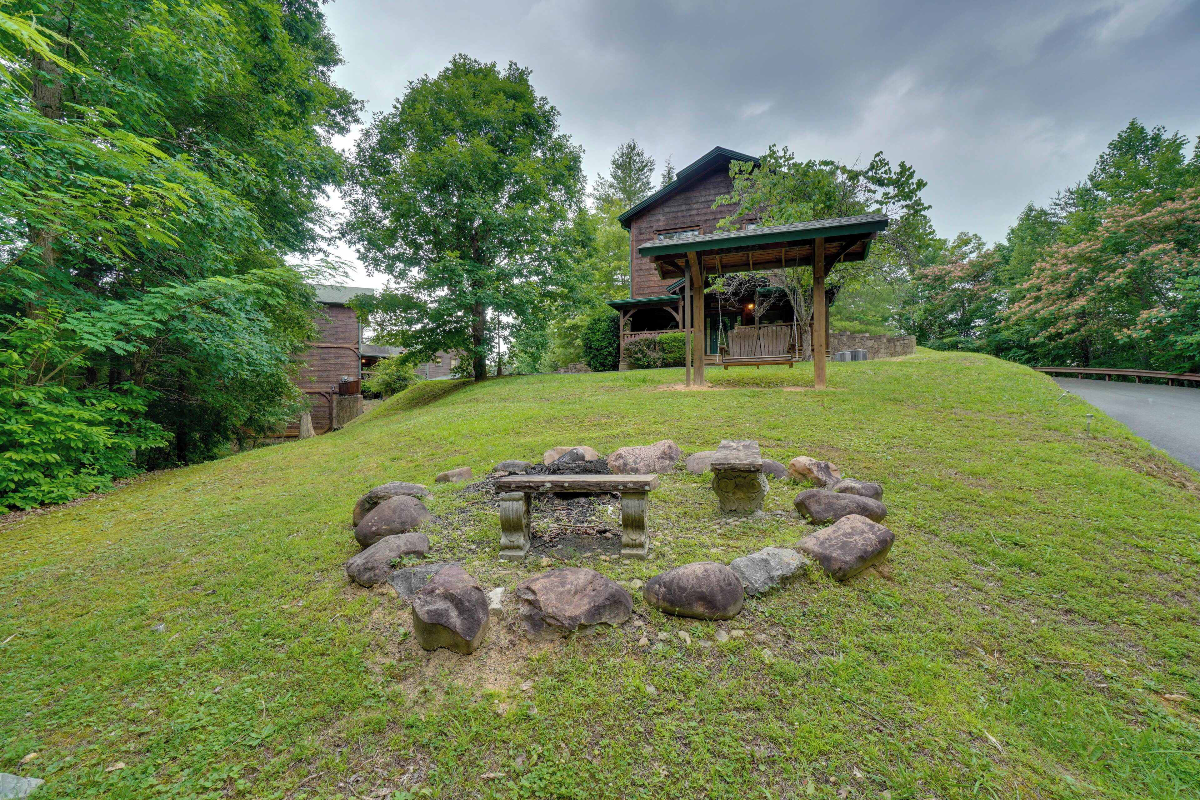 A gazebo with a stone fire pit in the center, surrounded by rocks.