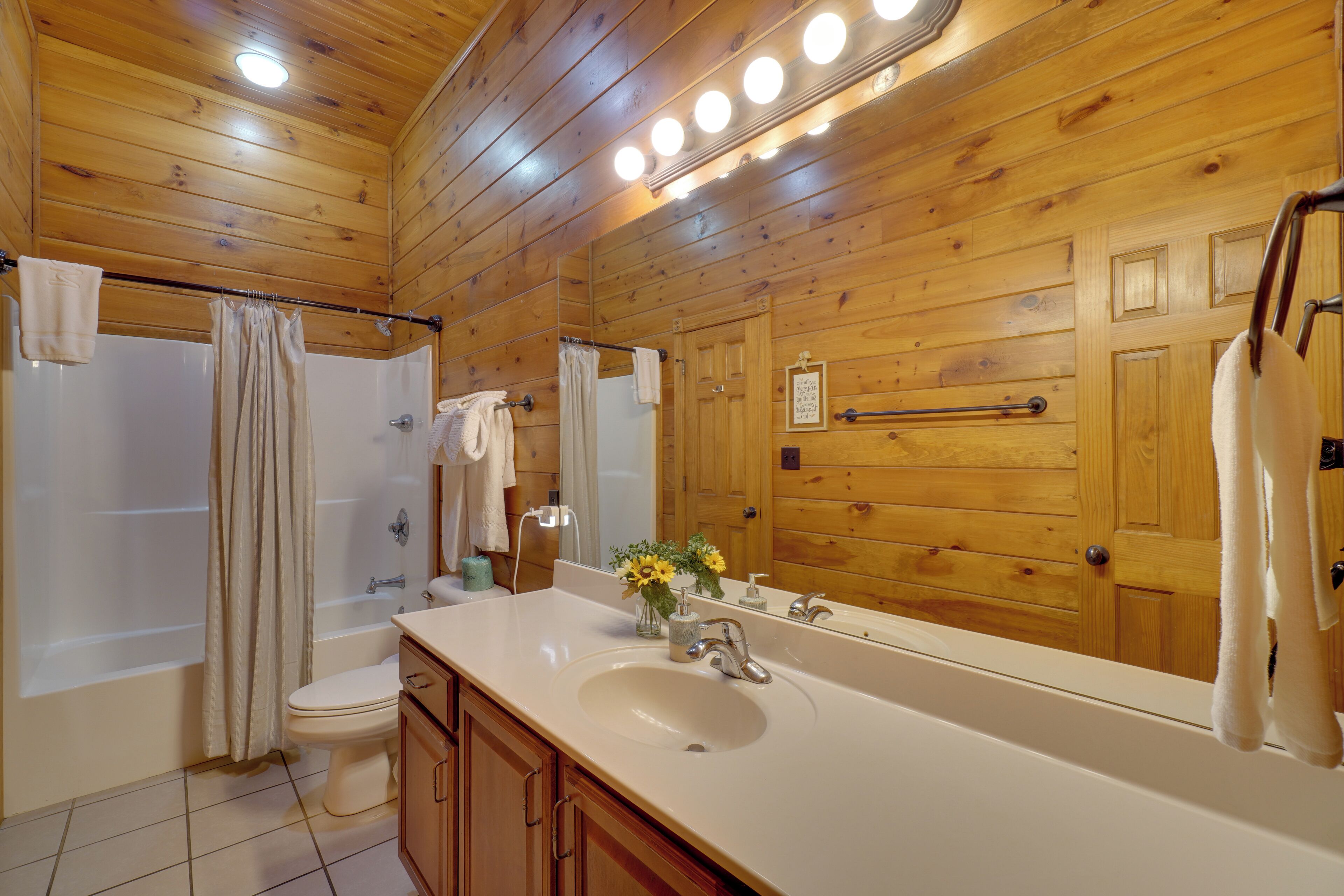 A wooden-paneled bathroom with a bathtub, toilet, and sink.