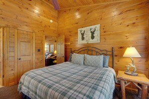 A wooden cabin-style bedroom with a bed, a headboard, a nightstand with a lamp, and a wall-mounted deer head decoration. - Hot Tub & Deck: Cabin Near Smoky Mtn Trails! (Sevierville)