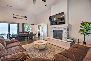 A spacious living room with a fireplace, a television mounted above it, and a dining area with a table and chairs.