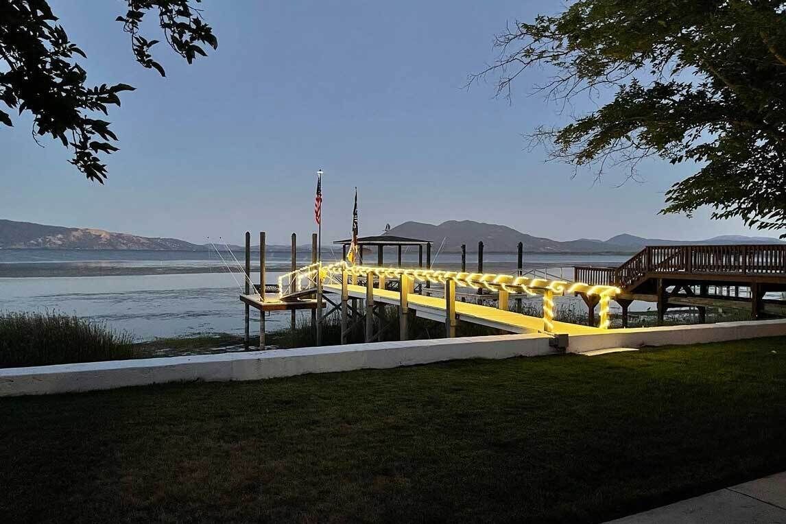 A dock with a yellow railing, a gazebo, and flags.