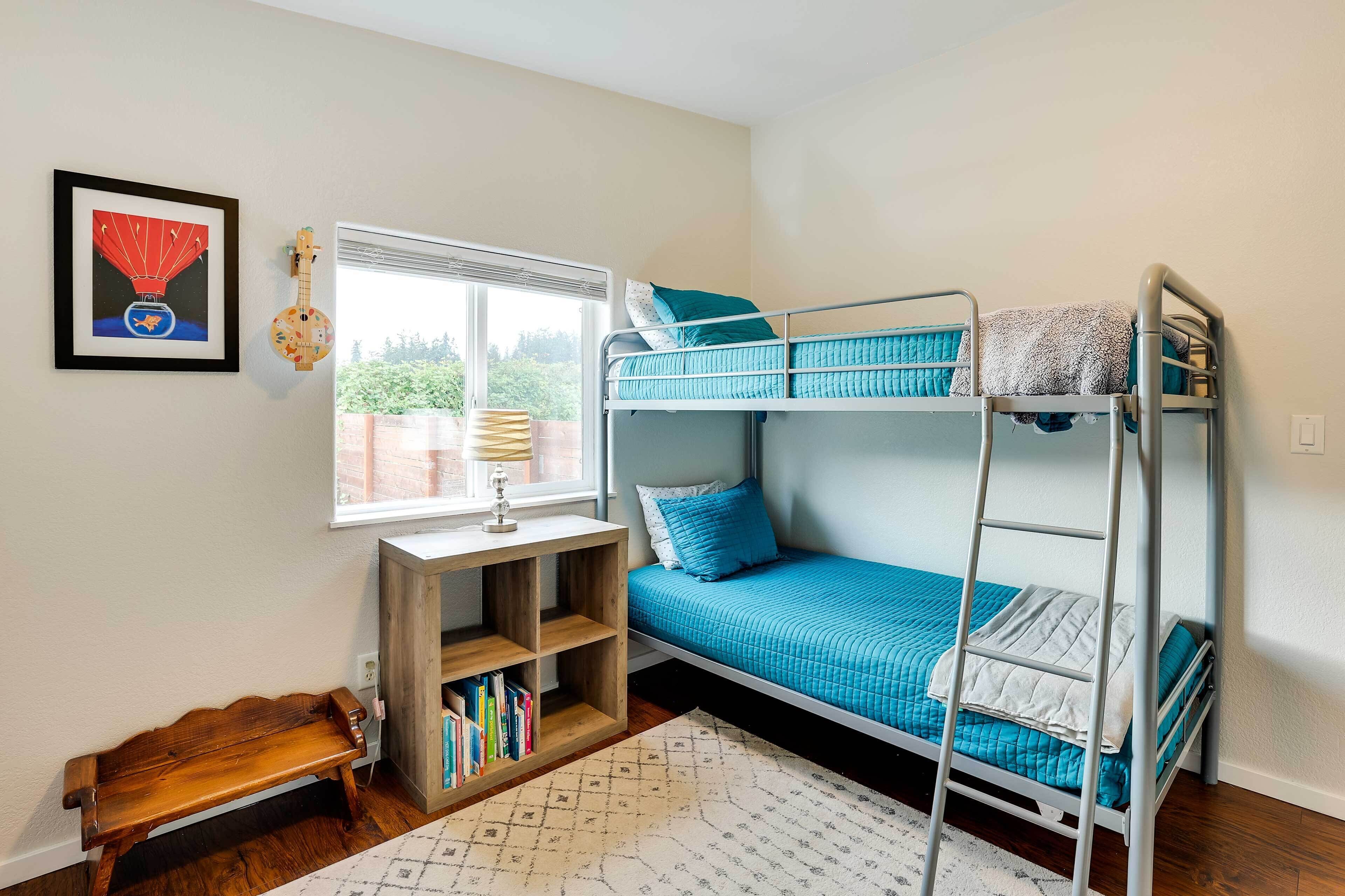 Een slaapkamer met een stapelbed, een raam, een boekenplank en een lijst aan de muur.