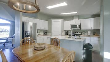 A modern kitchen with white cabinets, a stainless steel refrigerator, and a built-in microwave.