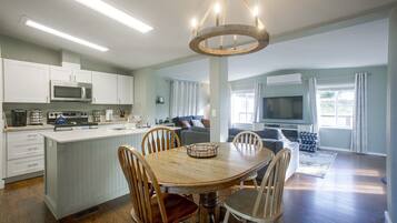 A modern kitchen with white cabinets, a central island, and a dining area with a wooden table and chairs.