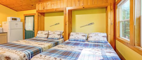 Une cabane équipée de deux lits, d’un réfrigérateur et d’une fenêtre donnant sur la forêt.