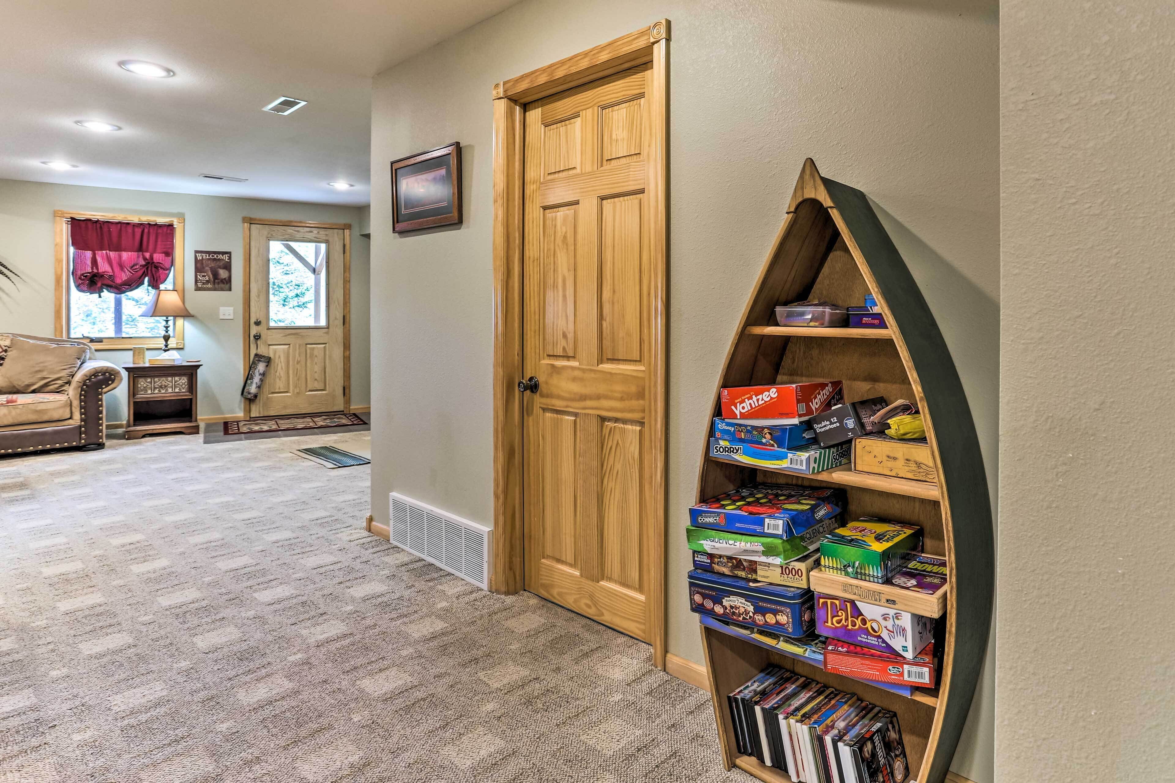 A hallway with a wooden door, a bookshelf with board games, a patterned carpet, and a couch in the background.