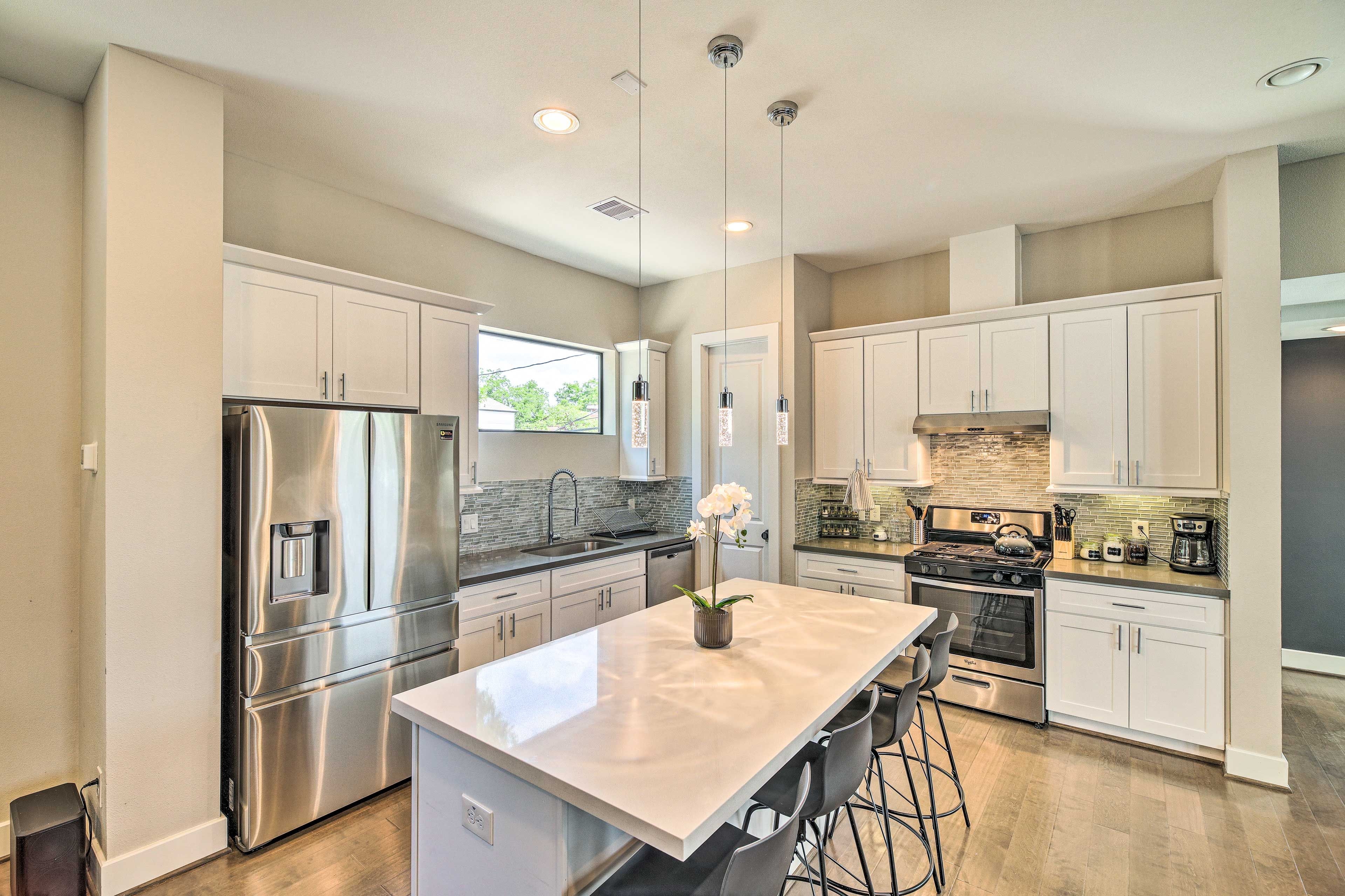 A modern kitchen with stainless steel appliances, a large island, and a view to the outdoors.