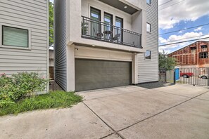A two-story residential building with a garage, a balcony with outdoor furniture, and a red vehicle parked nearby. - 3 Mi to Daikin Park: Gated Houston Townhome (Houston)