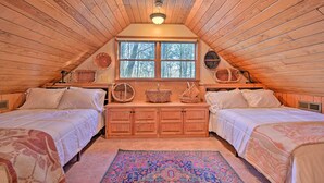 A cozy attic bedroom with two beds, a large window, and wooden beams. - Serene Cabin w/ Riverfront Views & Access! (Fayetteville)