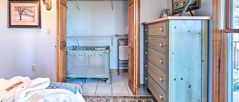 Un dormitorio con cama, cómoda, armario abierto y radiador.