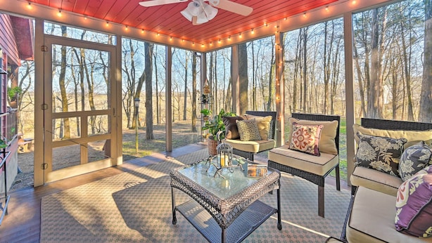 A covered outdoor seating area with a ceiling fan, string lights, and a glass table. - Serene Cabin w/ Riverfront Views & Access! (Fayetteville)