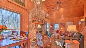 A wooden interior with a stone fireplace, dining area, and a cozy seating area with a fireplace. - Serene Cabin w/ Riverfront Views & Access! (Fayetteville)