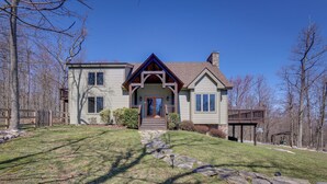 A two-story house with a stone pathway leading to the front door, surrounded by trees and a wooden deck. - Spacious Virginia Vacation Rental w/ Yard & Sauna (Purcellville)