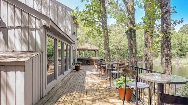 A wooden deck with outdoor seating, overlooking a body of water, and a building with large windows. - 15 Mi to University of Memphis: Getaway w/ Games (Southaven)
