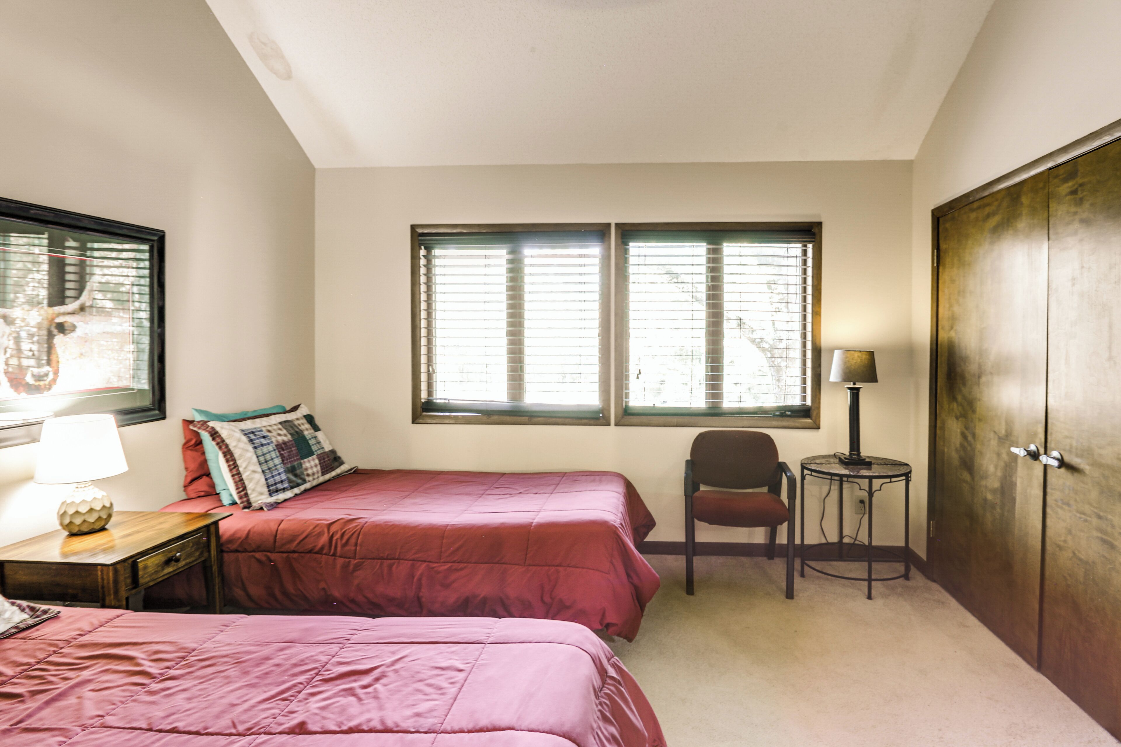 A bedroom with two beds, a chair, a small table, and a wardrobe.