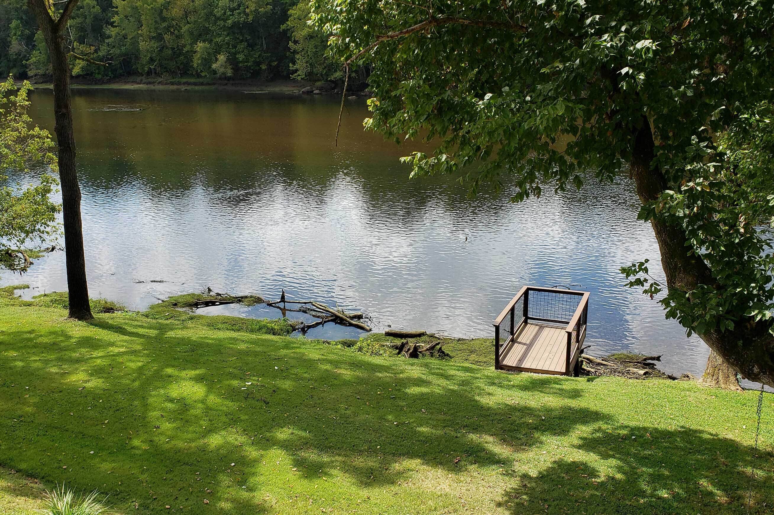 Um ambiente tranquilo à beira do lago, com um píer de madeira e um gramado.
