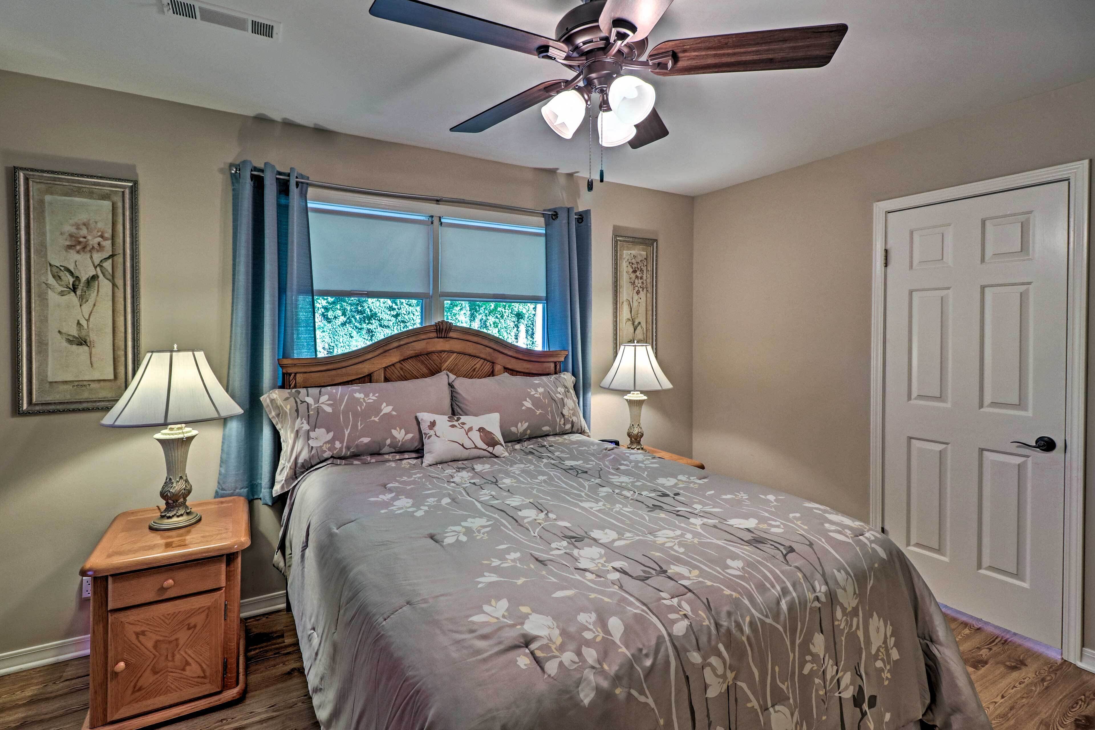 A bedroom with a bed, two bedside tables, a ceiling fan, and a window with curtains.