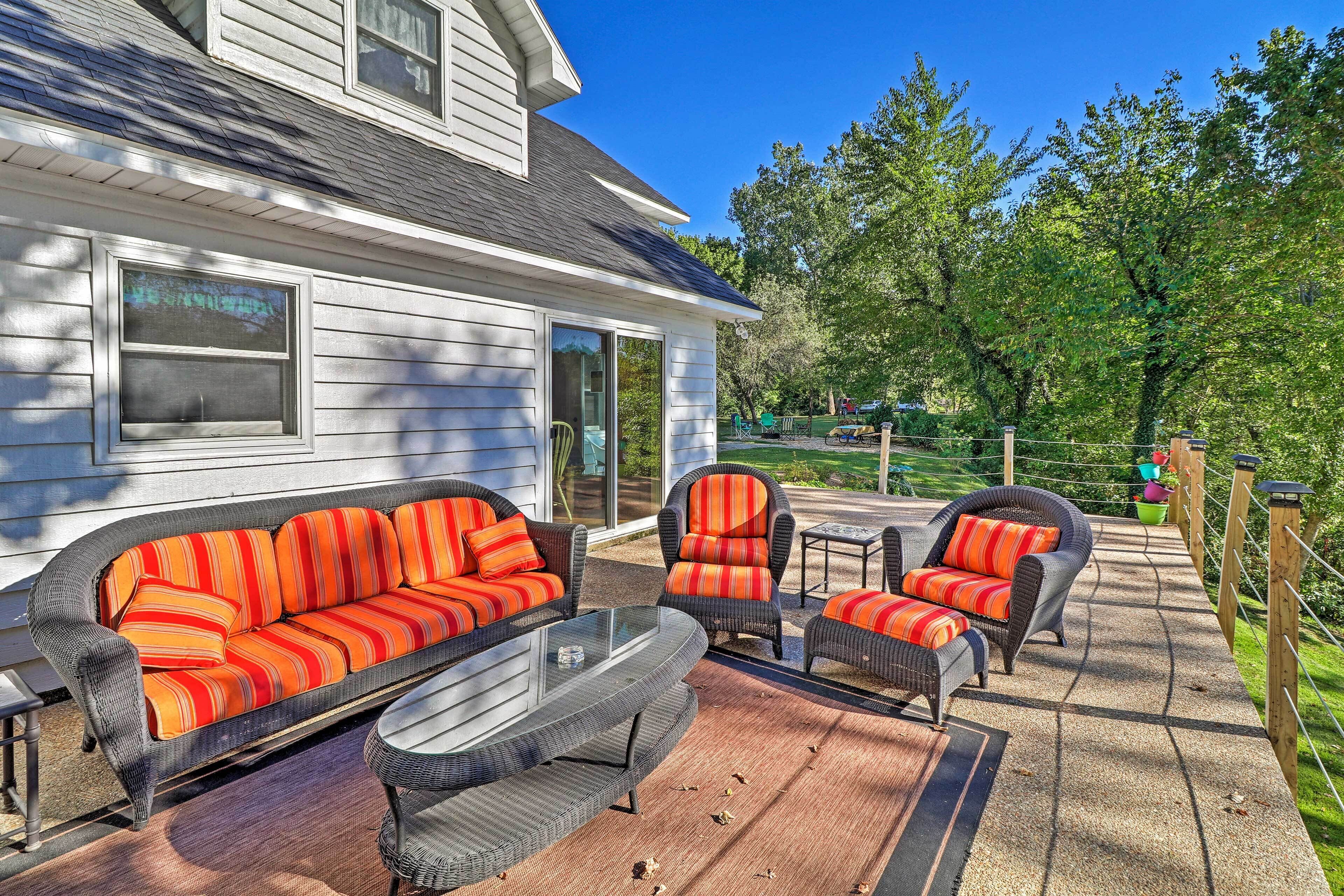 Eine überdachte Terrasse mit Korbmöbeln und gestreiften Kissen.