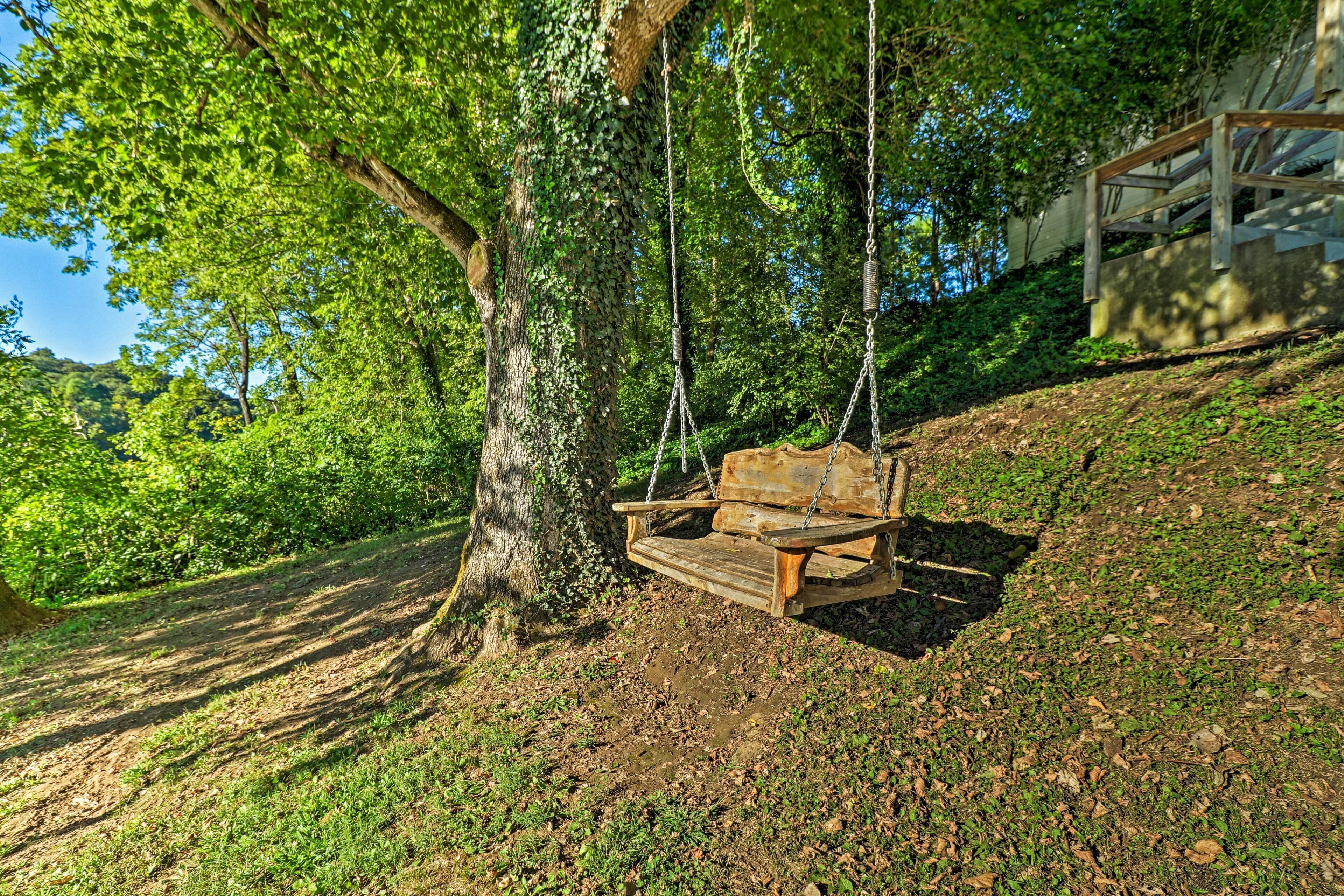 A wooden swing hanging from a tree in a park.