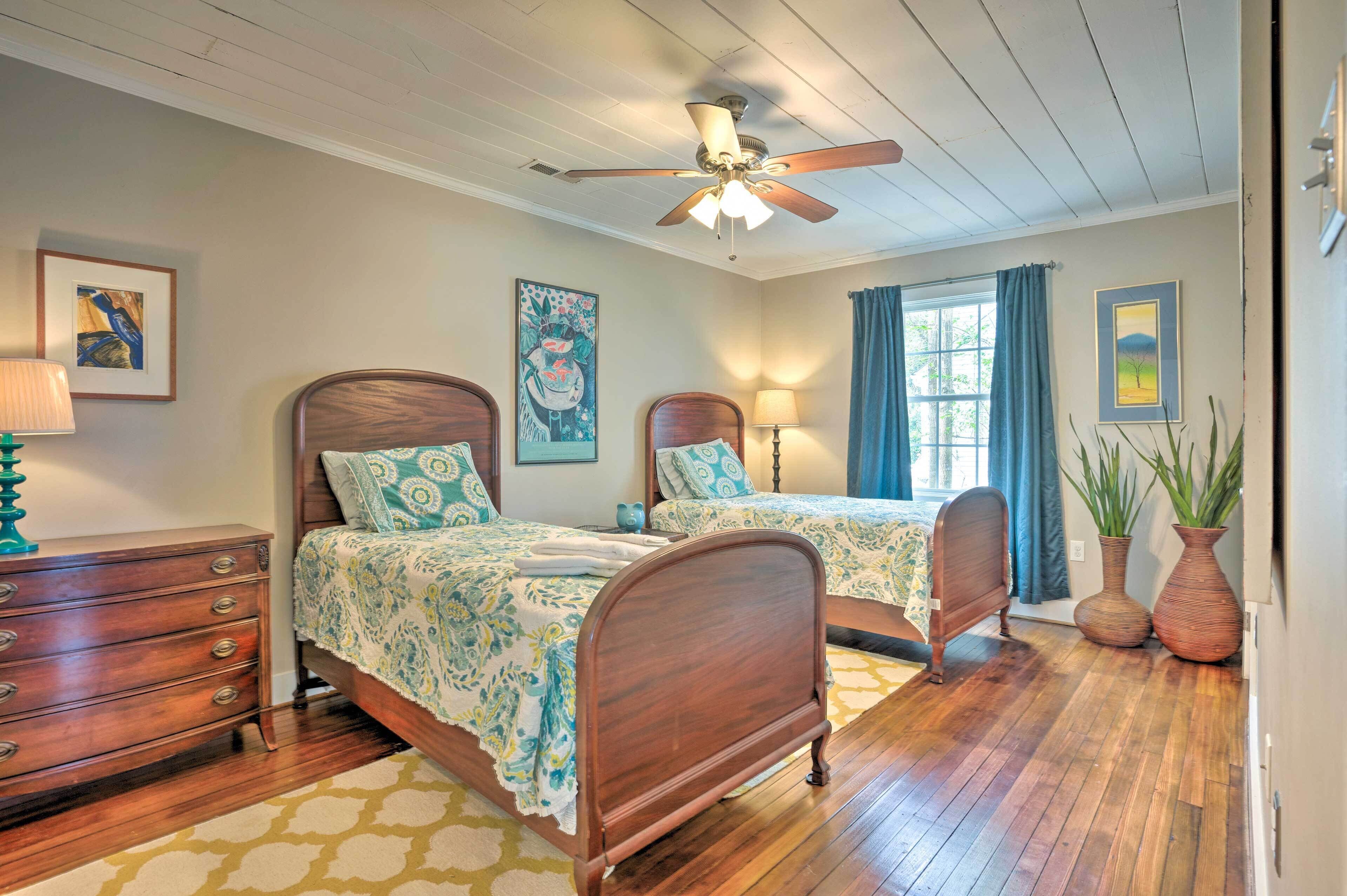 A bedroom with two wooden beds, a ceiling fan, and a window with curtains.