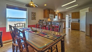 A spacious kitchen with wooden cabinets, a large island with chairs, and a view of the beach. - 'the Fishing House' Buena Vista Home w/ Mtn Views! (Buena Vista)
