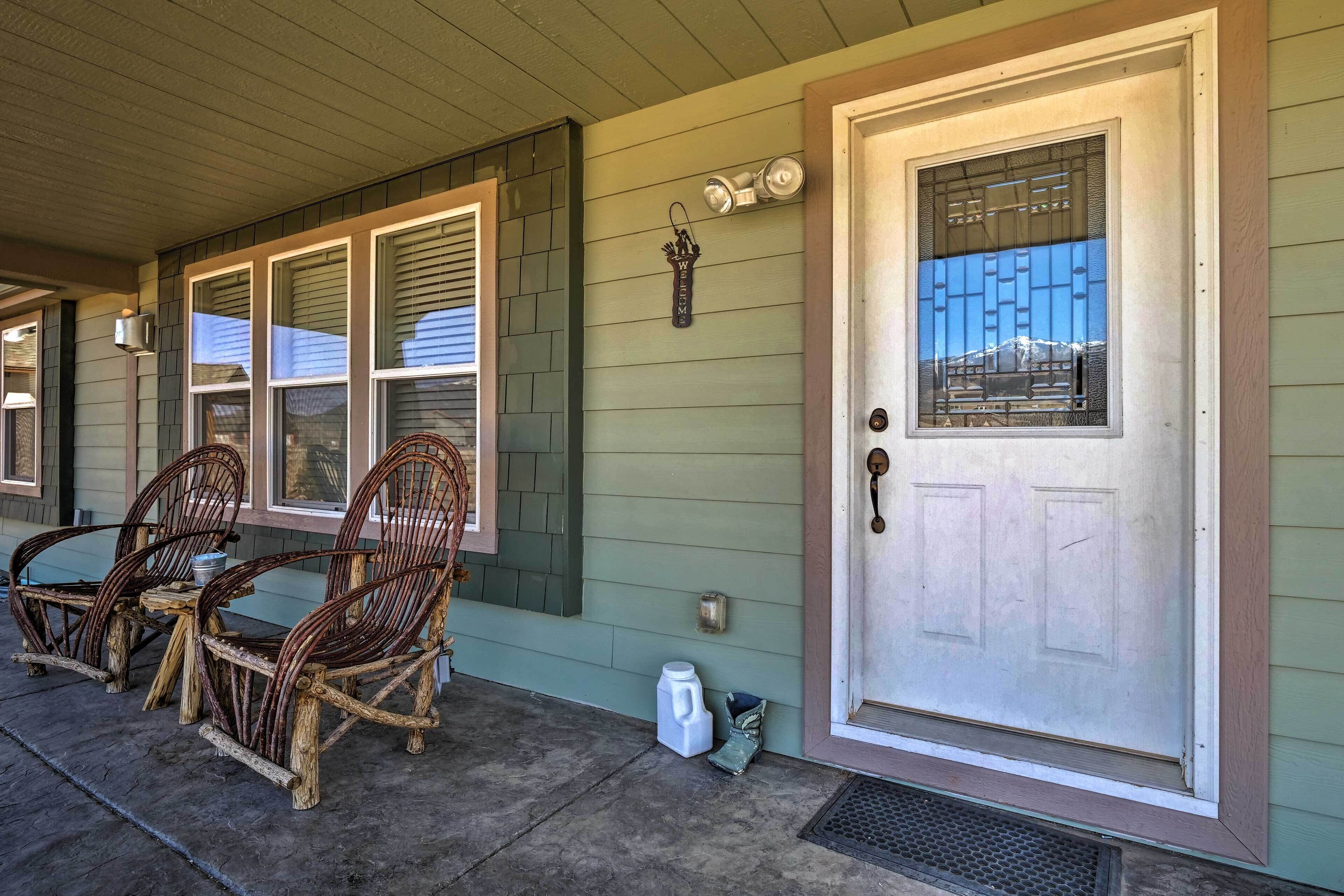 A porch with wicker rocking chairs and a door with a window.