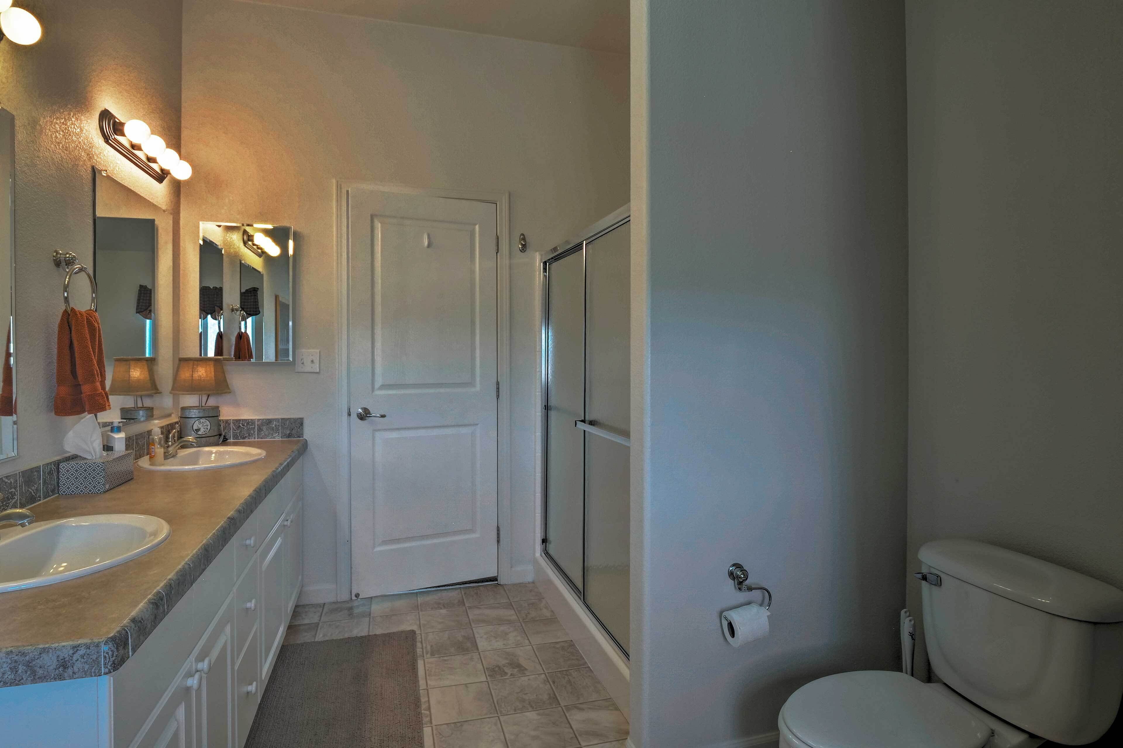A bathroom with two sinks, a toilet, a shower, and a door.