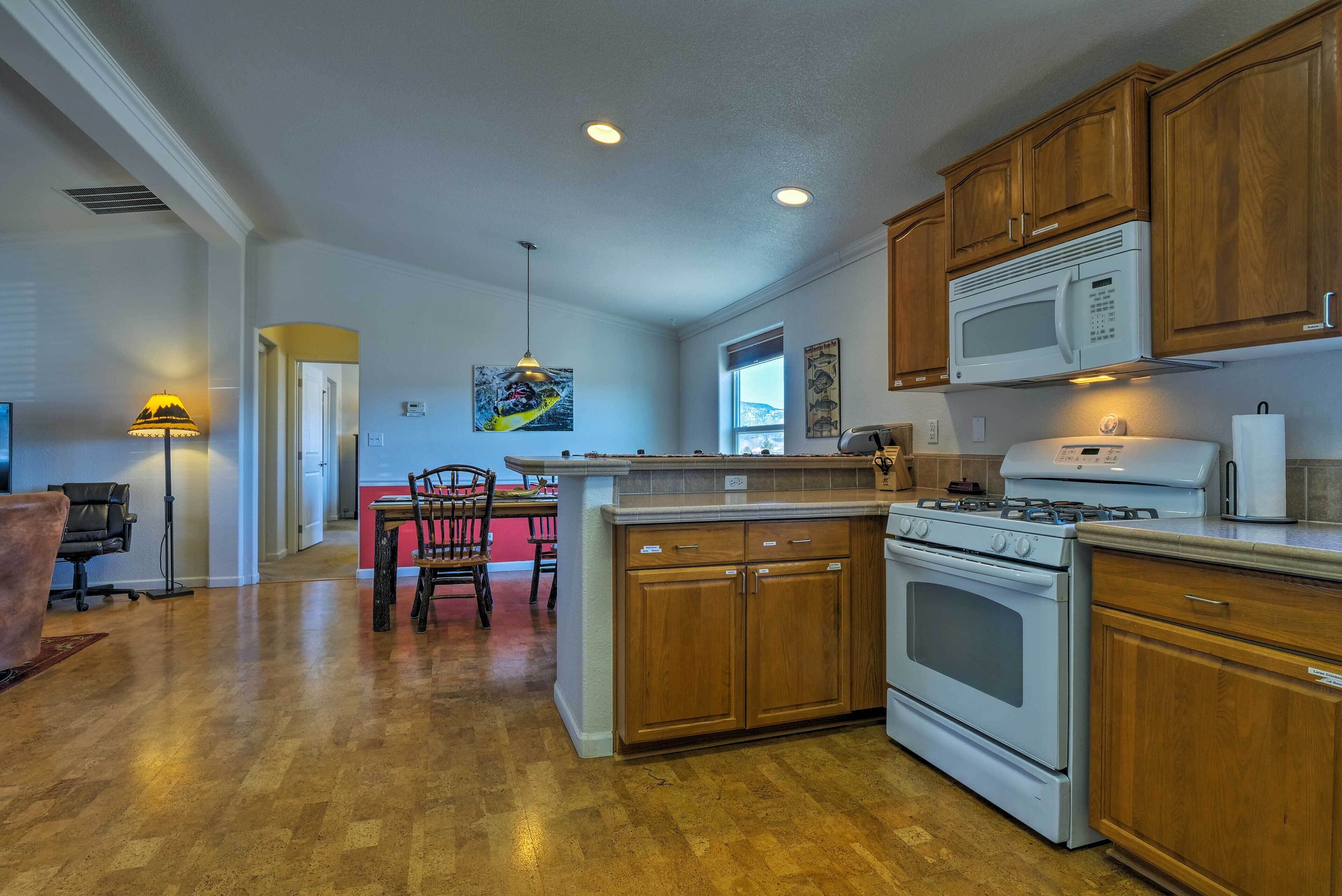 A kitchen with wooden cabinets, a microwave, an oven, and a dining area with a chair and table.