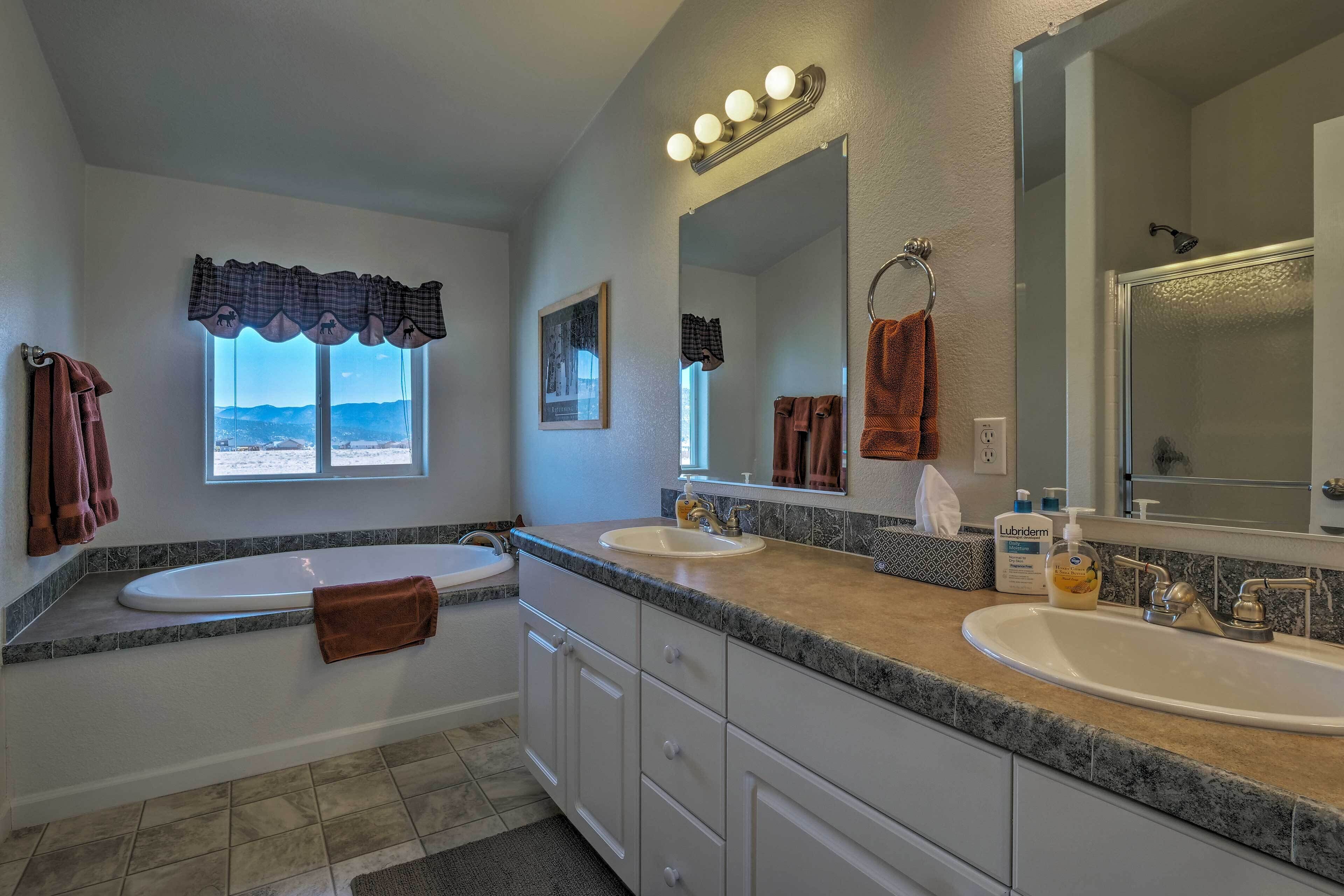 A bathroom with two sinks, a large mirror, and a window with a view of mountains.