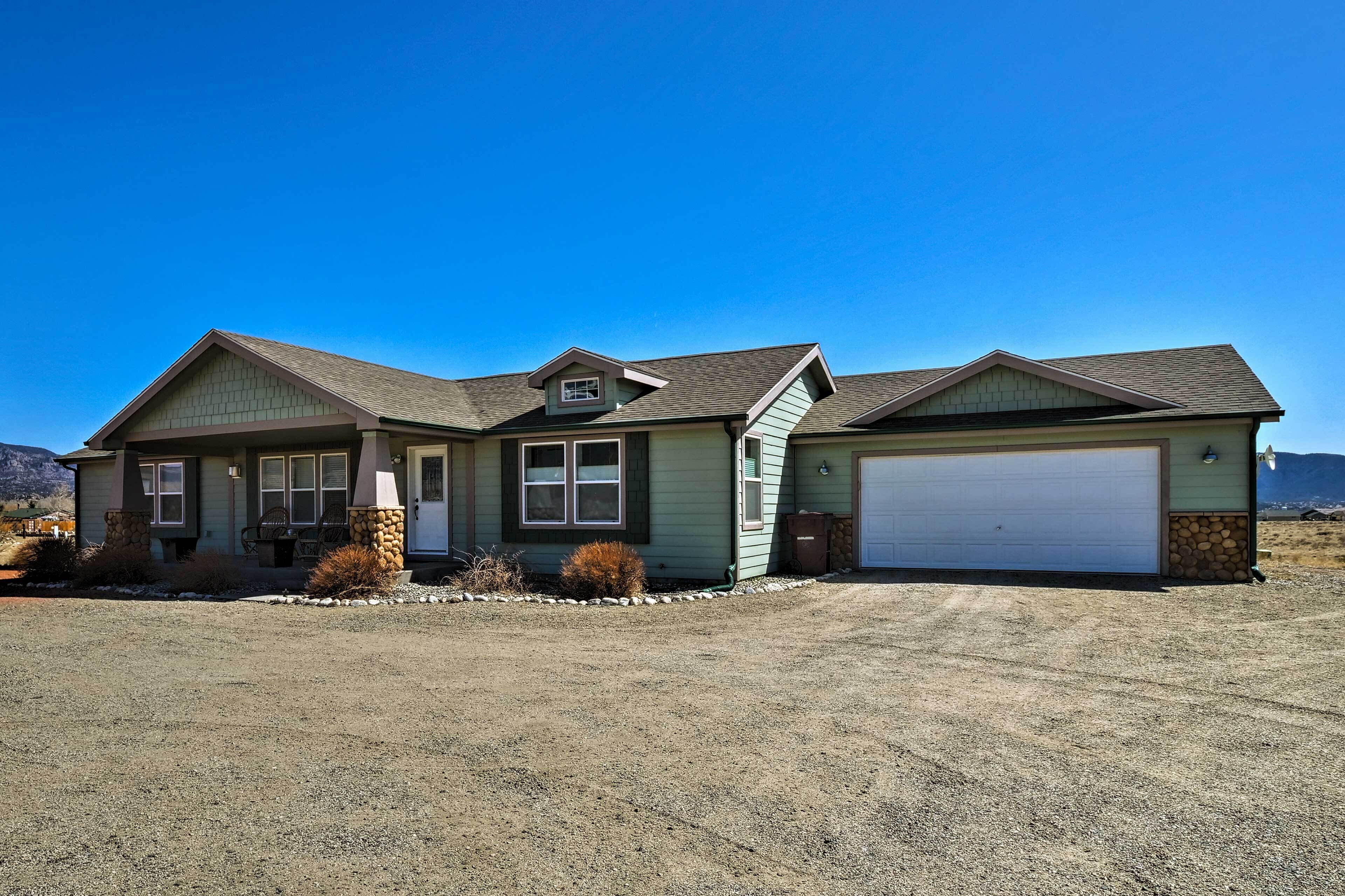 A two-story house with a garage, a front porch, and a stone foundation.