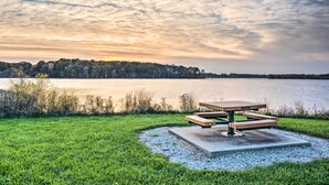 A picnic table by a lake with a grassy area and trees in the background. - Rustic Keosauqua Gem: Fire Pit & Lake Sugema Views (Keosauqua)