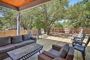 Un patio al aire libre con terraza de madera, mobiliario de mimbre y zona de estar cubierta.