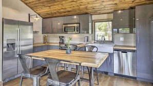 A modern kitchen with stainless steel appliances, a wooden ceiling, and a dining area with metal chairs. - Updated Cabin w/ Hot Tub ~ 11 Mi to Winter Park! (Winter Park)