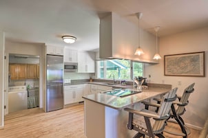 A modern kitchen with stainless steel appliances, a central island with bar stools, and pendant lighting.