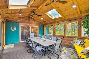 A wooden interior with a dining table and chairs, a yellow sofa, and a ceiling fan.