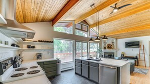 Une cuisine moderne dotée d’un grand îlot central, d’appareils électroménagers en acier inoxydable et d’un plafond en bois.