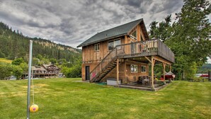 A wooden cabin with a balcony, a staircase, and a grassy yard. - Waterfront Cabin w/ 2 Boat Docks & Mtn Views! (St. Maries)
