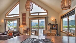 A spacious living area with a large island stove, multiple windows offering scenic views, and a cozy seating arrangement. - Waterfront Cabin w/ 2 Boat Docks & Mtn Views! (St. Maries)