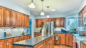 Una cocina amplia con armarios de madera, un refrigerador de acero inoxidable y una encimera de granito.