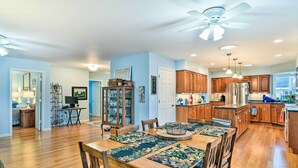 Una cocina amplia con armarios de madera, una isla central y un comedor con camino de mesa floral.