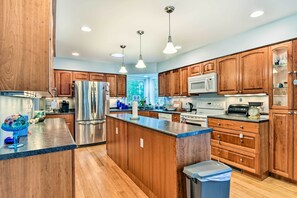 A modern kitchen with wooden cabinets, stainless steel appliances, and pendant lighting. - Waterfront Gladwin Home w/ Deck + Fire Pit! (Gladwin)