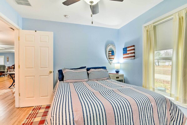 A bedroom with a bed, a ceiling fan, a window with curtains, and a door leading to another room. - Waterfront Gladwin Home w/ Deck + Fire Pit! (Gladwin)