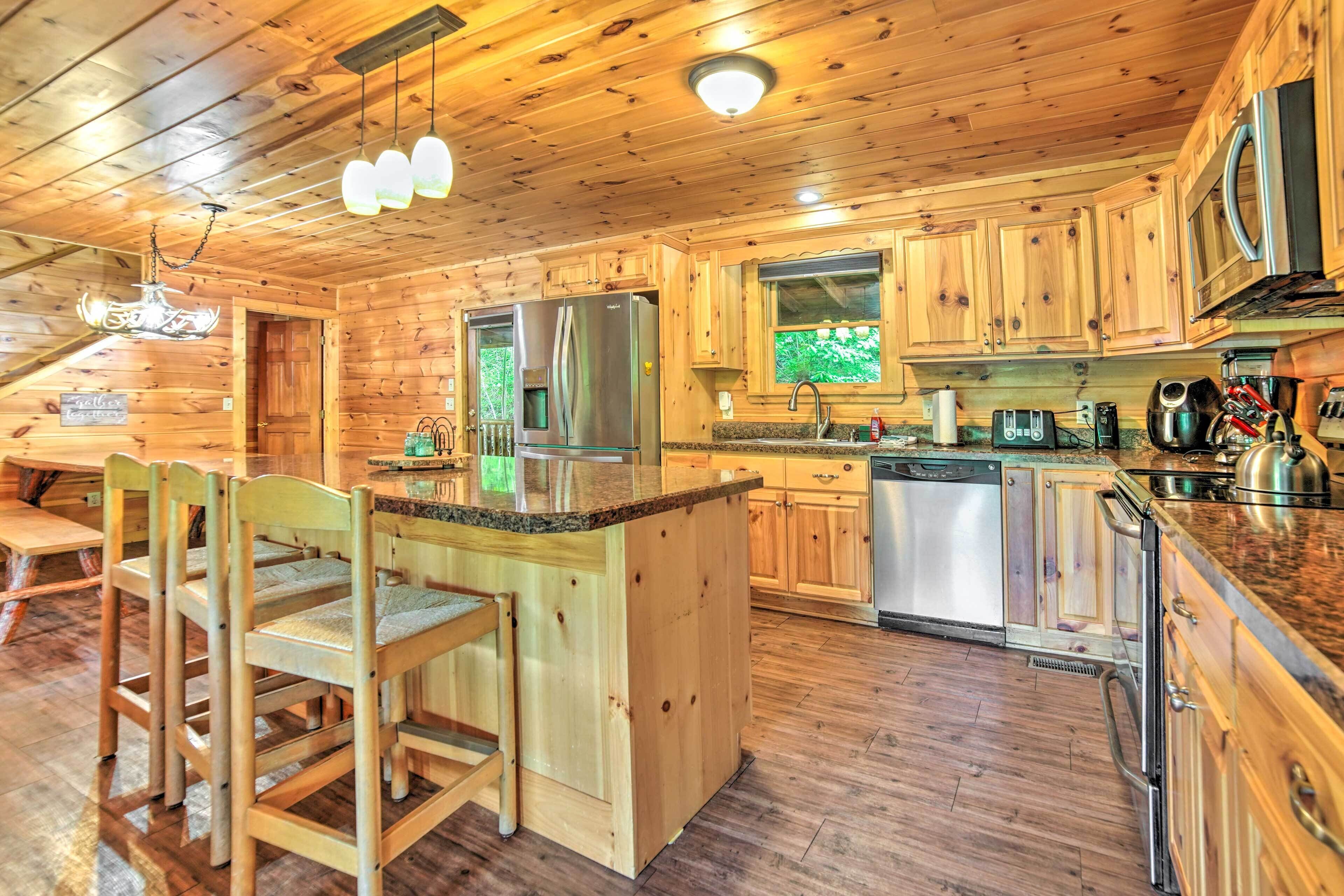 L’intérieur d’une cabane en bois comprend un coin cuisine équipé d’un réfrigérateur, d’un four à micro-ondes et de meubles de rangement en bois.