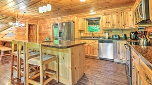 A wooden cabin interior with a kitchen area featuring a refrigerator, microwave, and wooden cabinets. - Games, Theater & Views: Gatlinburg Gem Near Trails (Gatlinburg)