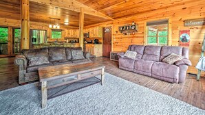 A rustic cabin interior with wooden walls and ceiling, a kitchen area, two sofas, and a 'Welcome' sign. - Games, Theater & Views: Gatlinburg Gem Near Trails (Gatlinburg)