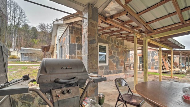 An outdoor patio area with a stone building, a grill, and a table. - Unplugged Bryson City Cabin Near Downtown (Bryson City)