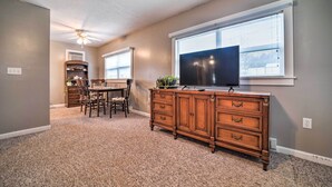 A room with a dining table, chairs, a wooden dresser, a television, and a ceiling fan. - Unplugged Bryson City Cabin Near Downtown (Bryson City)