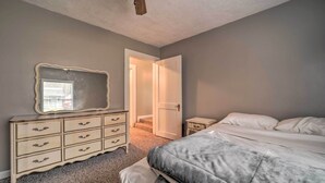 A bedroom with a bed, dresser, mirror, and a door leading to another room. - Unplugged Bryson City Cabin Near Downtown (Bryson City)